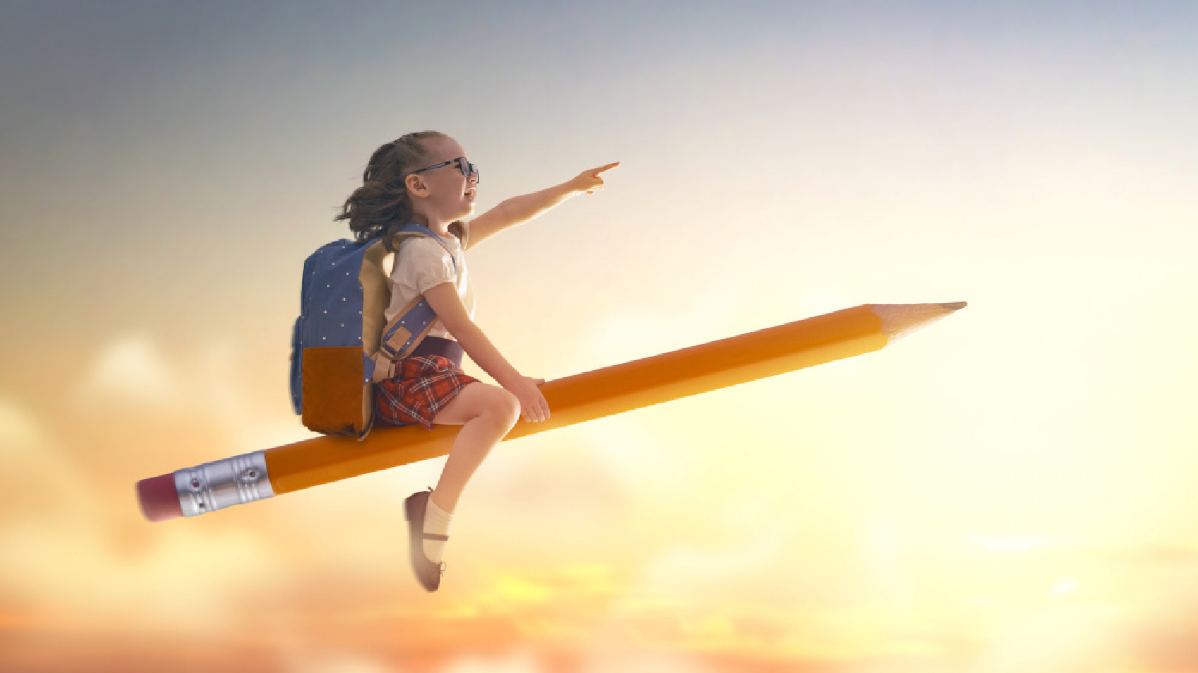 Back to school! Happy cute industrious child flying on the pencil on background of sunset sky. Concept of education and reading. The development of the imagination.